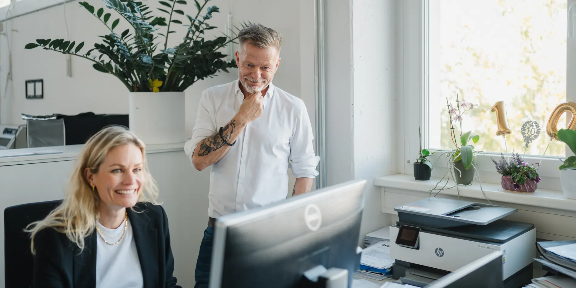 Zwei Kolleginnen und Kollegen im Büro der adequapharm, eine am Bildschirm, einer daneben stehend